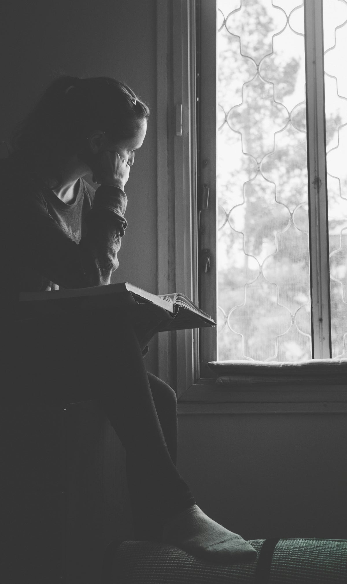 A person standing thoughtfully beside a rain-covered window, reflecting quietly in a calm monochrome setting that represents mental clarity and intentional living.