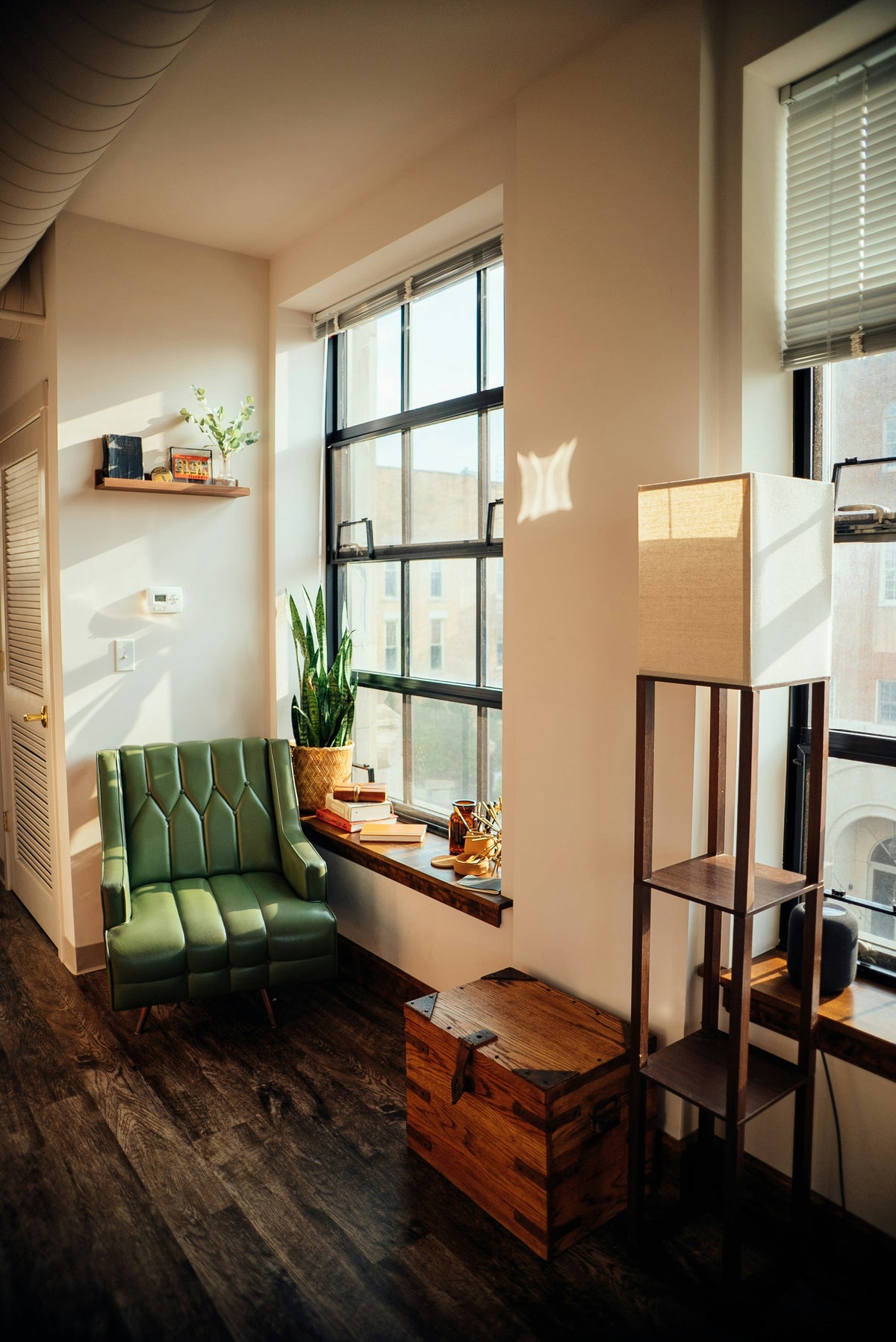 Modern interior with a green sofa, wooden crate, and large window.